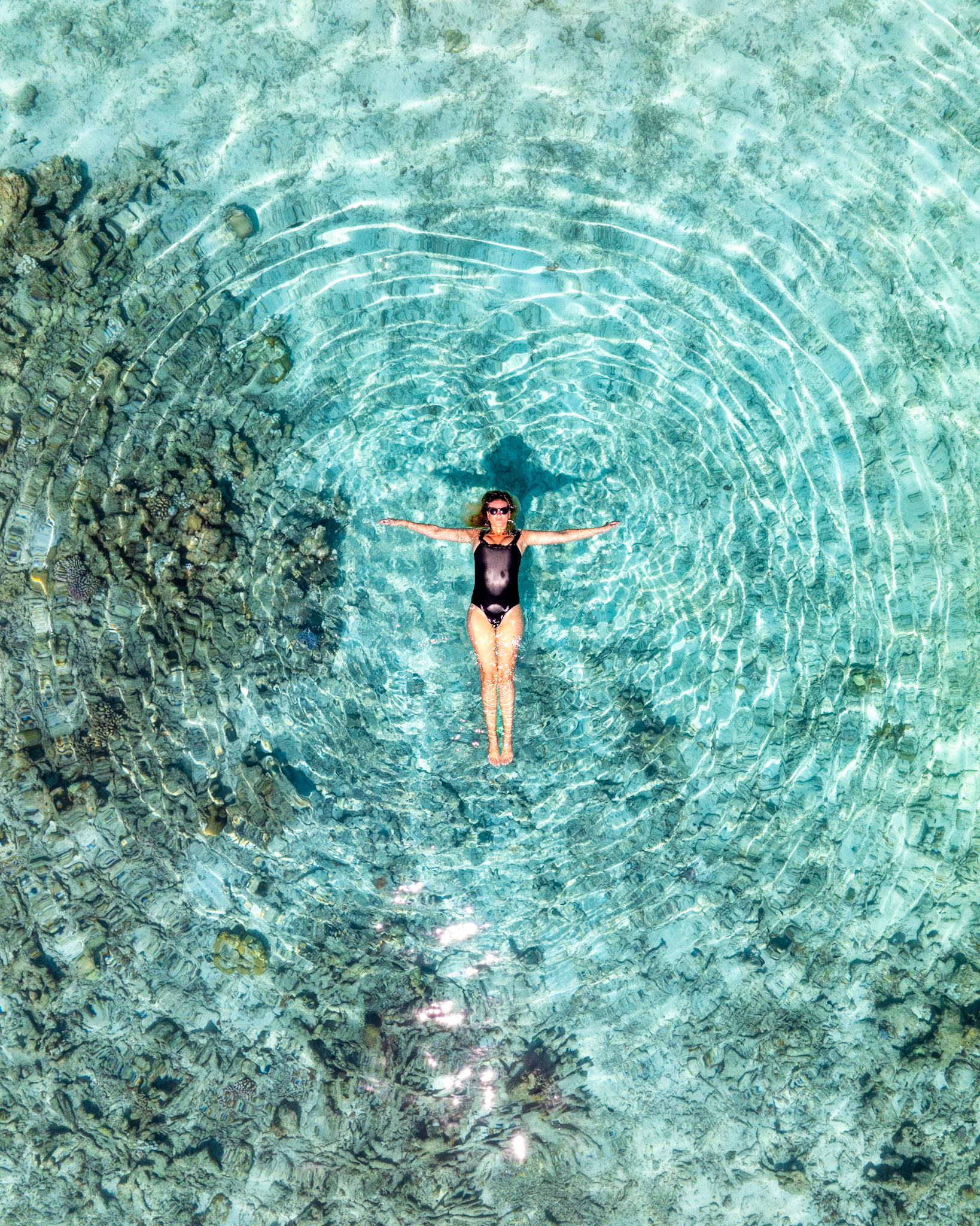 Woman floating in crystal clear Maldives water